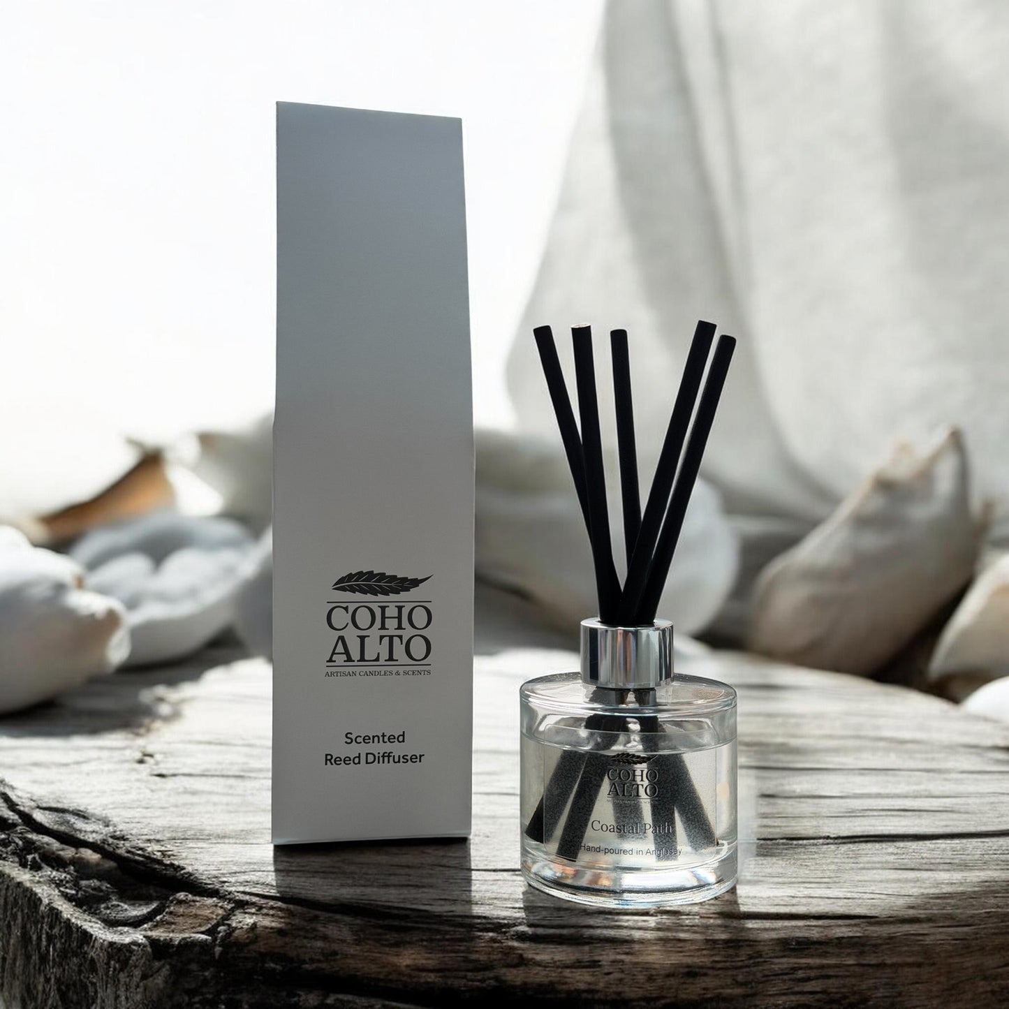 Coho Alto scented reed diffuser on a wooden surface with packaging in the background.