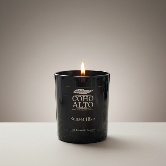 Candle in a black container labeled 'Coho Alto Sunset Hike' on a neutral background