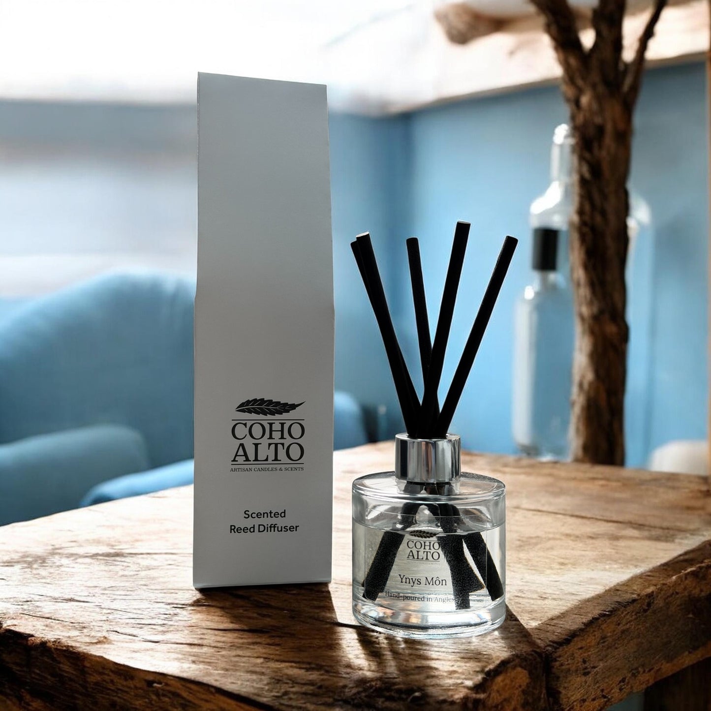 Coho Alto Anglesey reed diffuser on a wooden surface with a blurred background