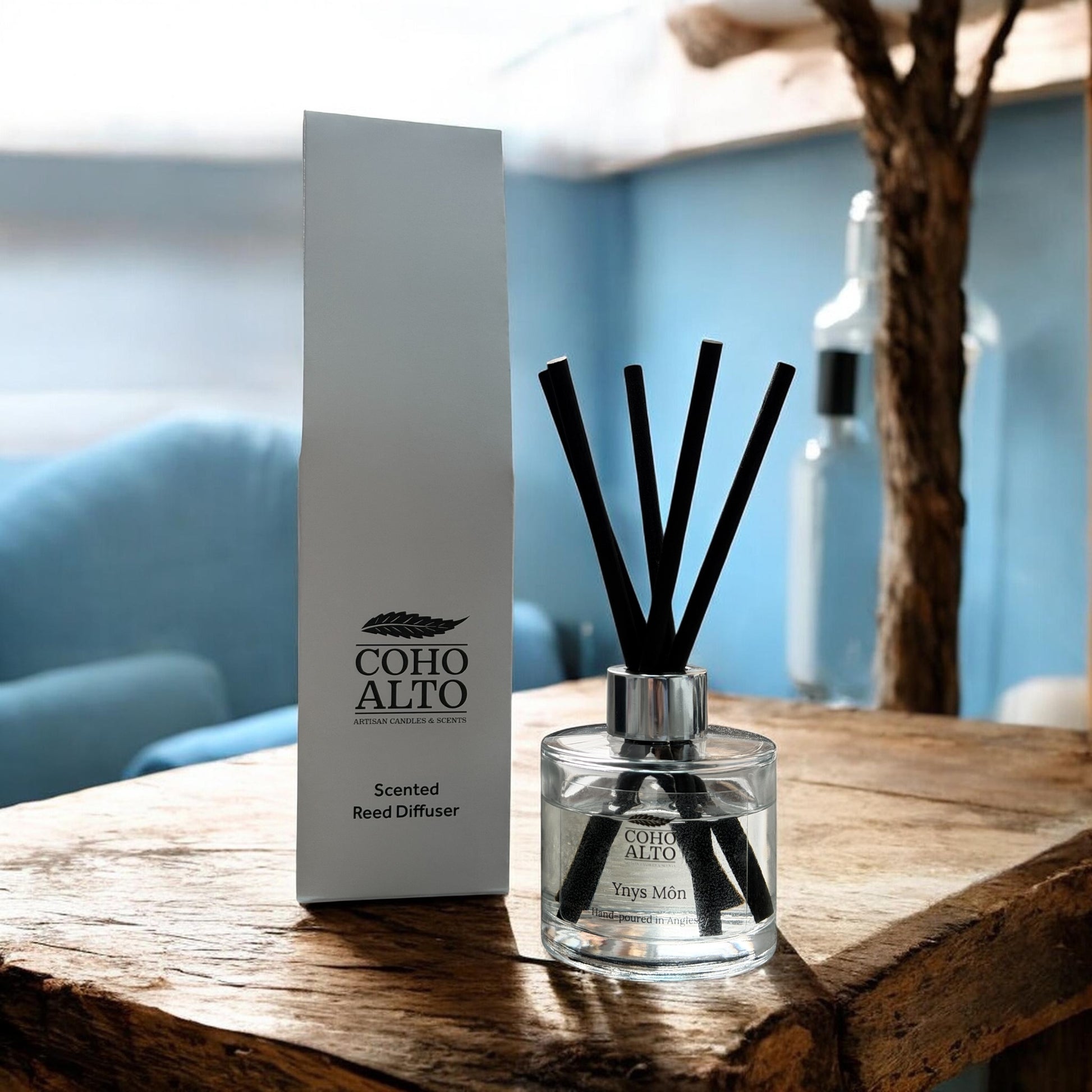 Coho Alto Anglesey reed diffuser on a wooden surface with a blurred background